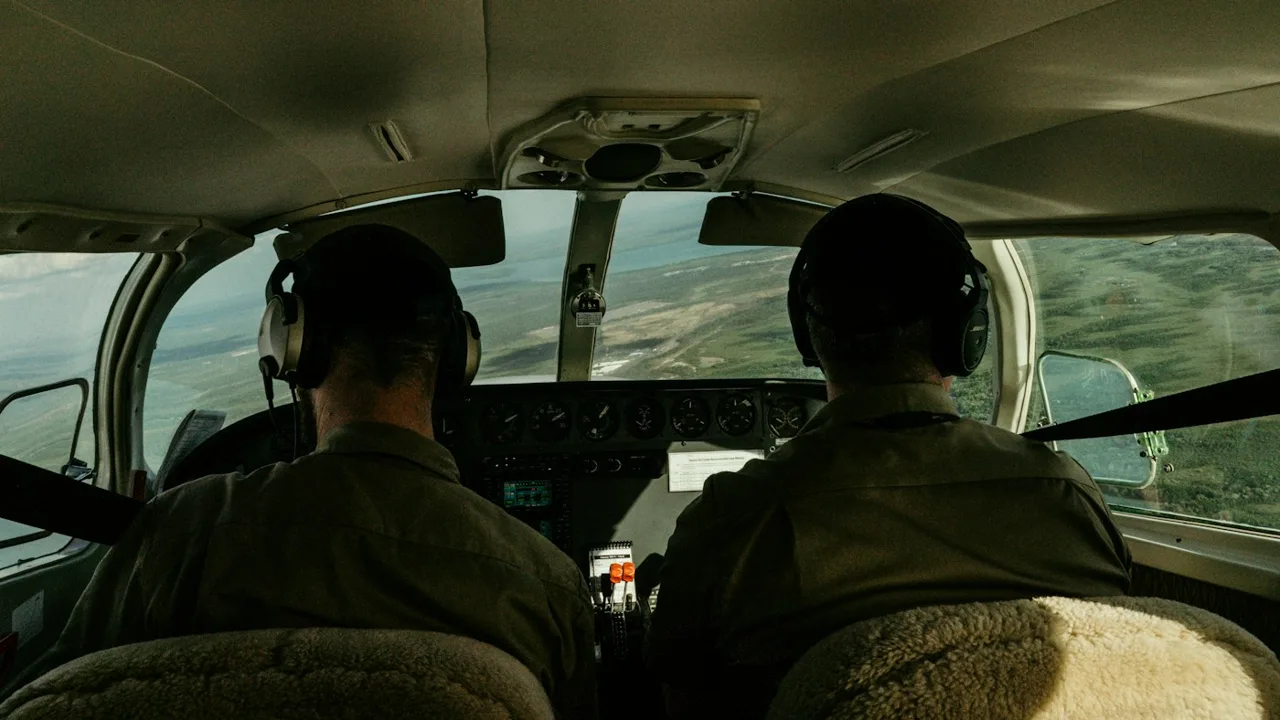 Two pilots wearing headsets working together in a flight deck